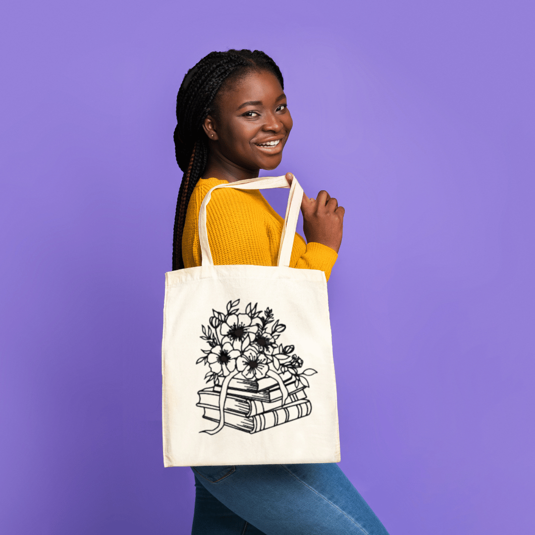 Woman holding a tote bag with a floral and book design against a purple background