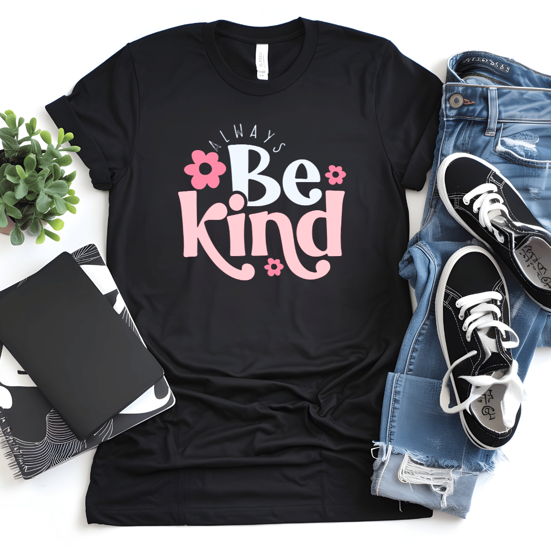 Black t-shirt with 'Always Be Kind' text, jeans, sneakers, and a notebook on a white surface.