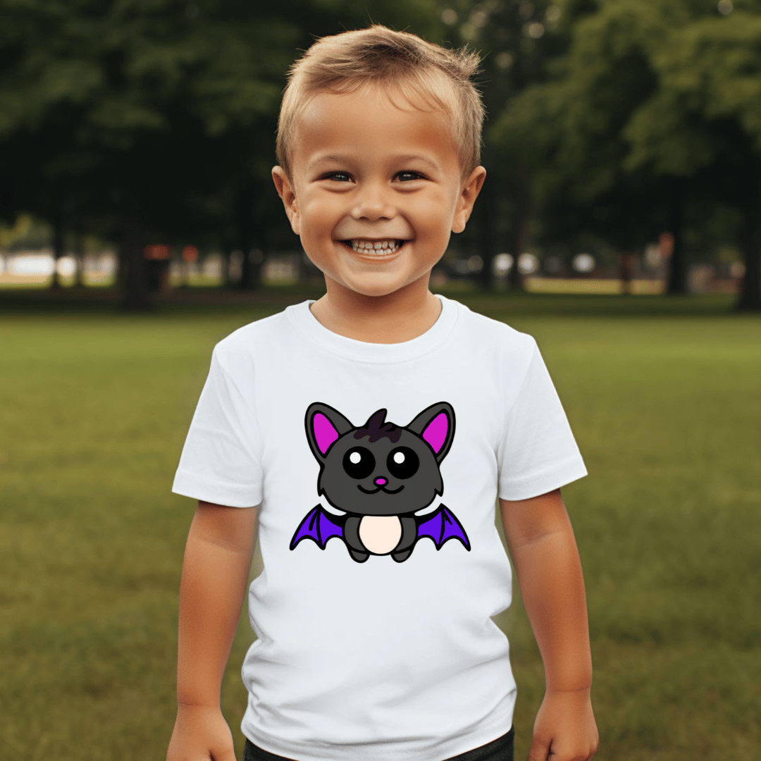 Child wearing a white t-shirt with a cartoon bat design outdoors.