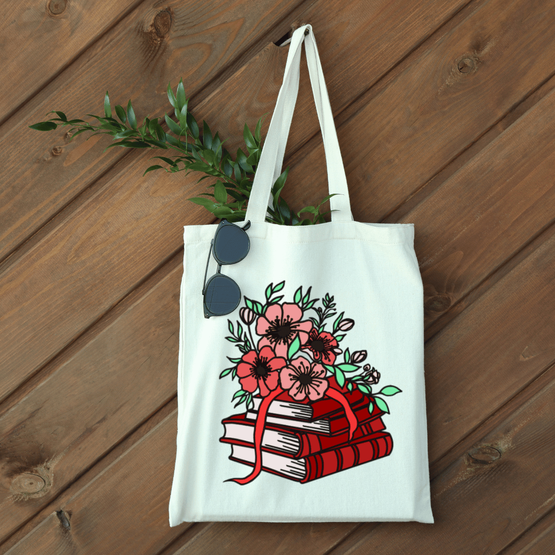 White tote bag with a red floral and book design on a wooden surface