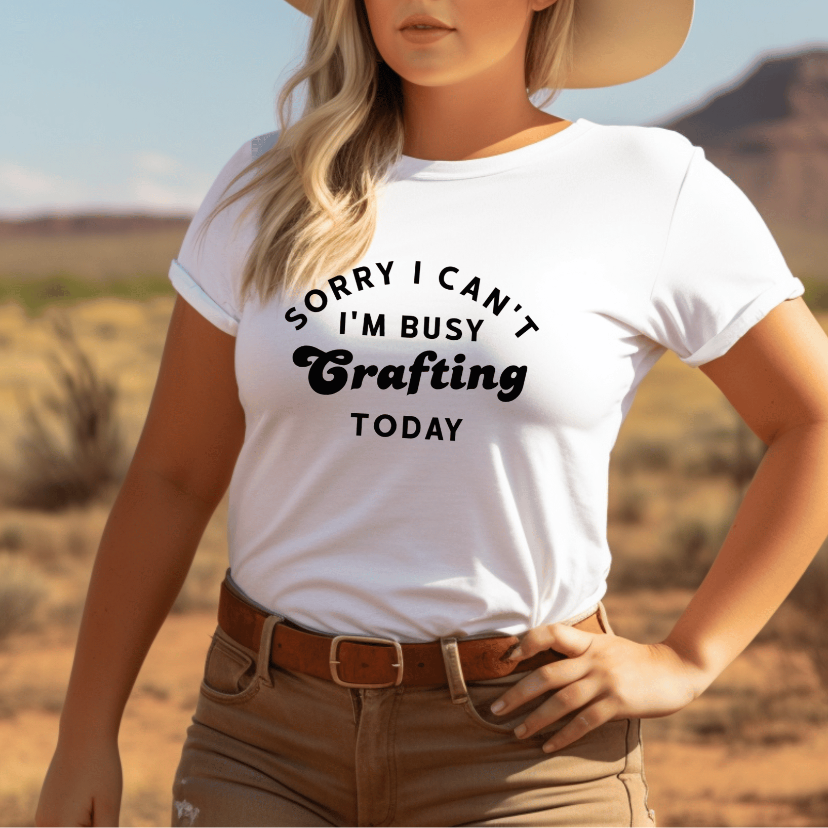Woman wearing a white t-shirt with 'Sorry I Can't I'm Busy Crafting Today' text in a desert setting.