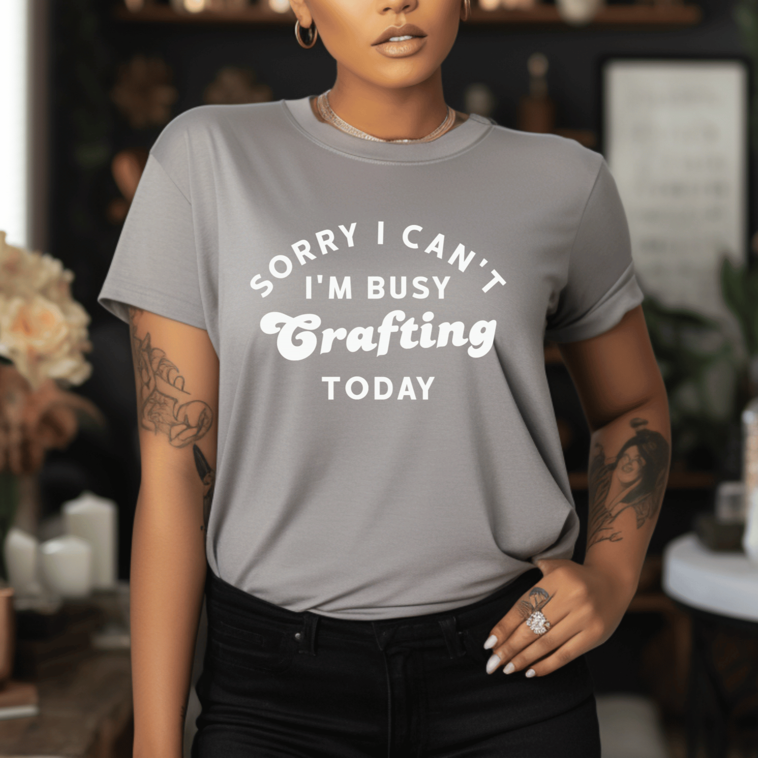 Woman wearing a gray t-shirt with text in a room with decorative elements.