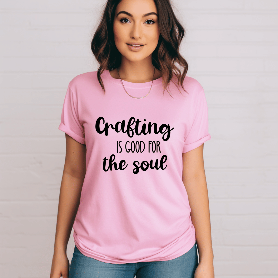 Person wearing a pink t-shirt with 'Crafting is good for the soul' text on a plain background