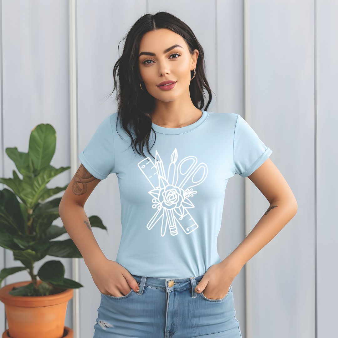 Woman wearing a light blue t-shirt with a white graphic design, standing against a light wooden panel background.