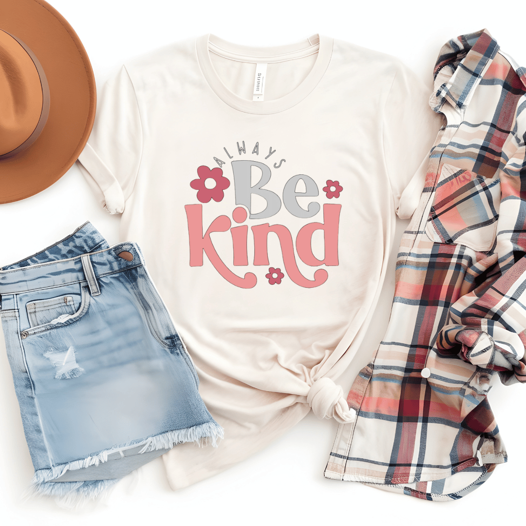 White t-shirt with 'Always Be Kind' text, denim shorts, plaid scarf, and brown hat on a white background