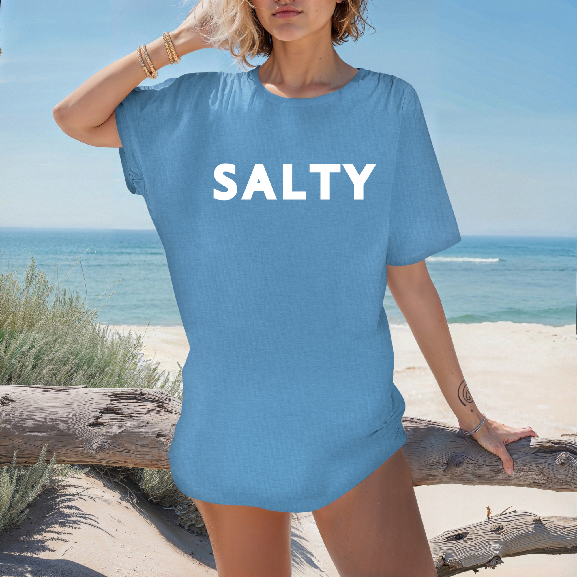 Woman wearing a blue t-shirt with 'SALTY' on it at the beach.