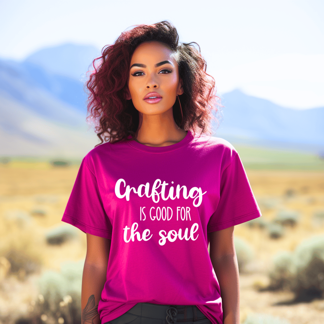 Woman wearing a pink t-shirt with 'Crafting is good for the soul' text in a desert setting