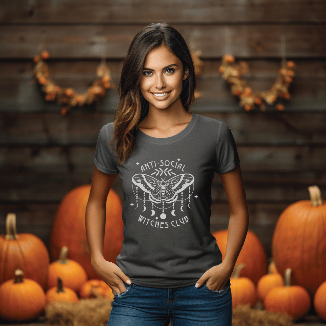 Woman wearing a dark grey t-shirt with a design in front of pumpkins and a wooden wall.