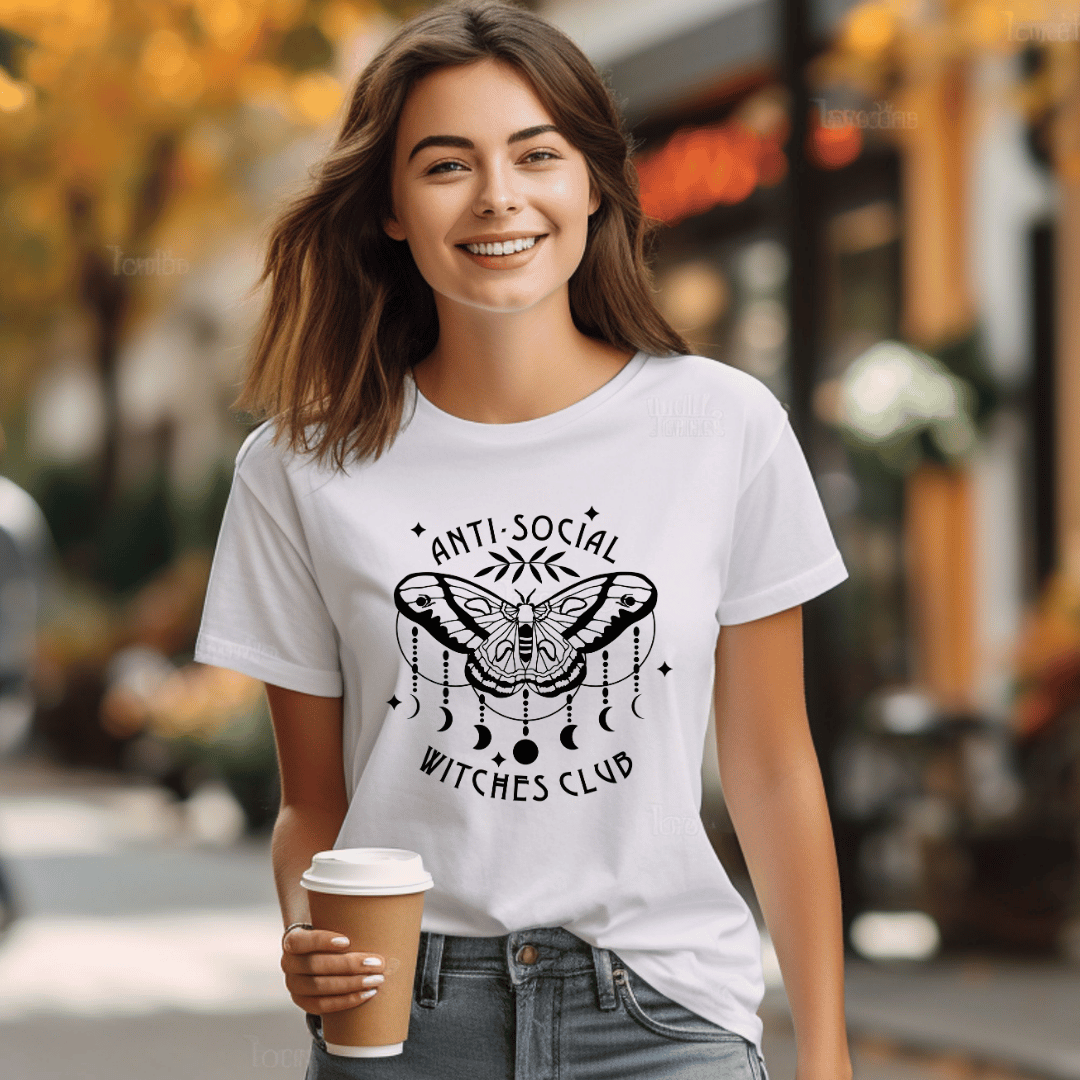 Woman wearing a white t-shirt with 'Anti-Social Witches Club' design, holding a coffee cup outdoors.