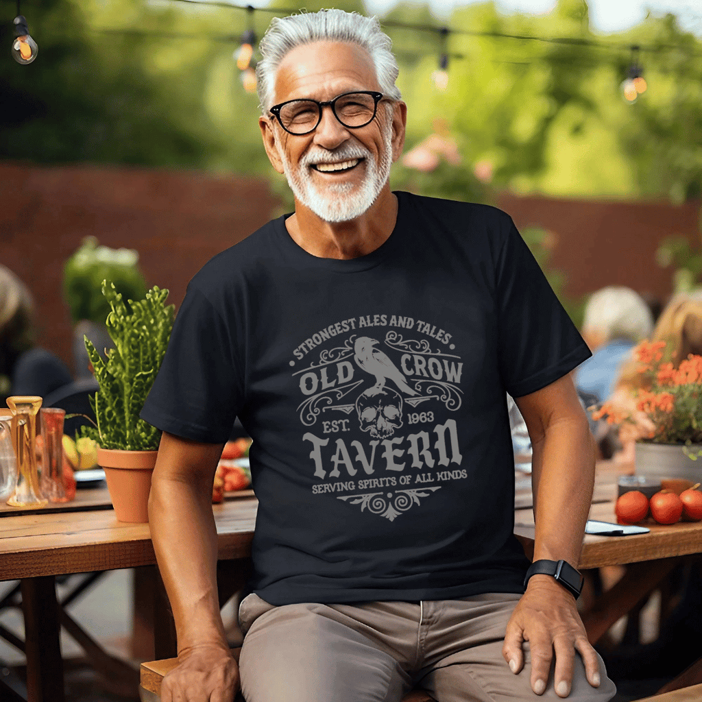 Man wearing a black t-shirt with 'Old Crow Tavern' design, sitting outdoors.