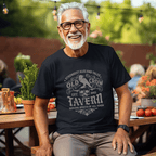 Man wearing a black t-shirt with 'Old Crow Tavern' design, sitting outdoors.
