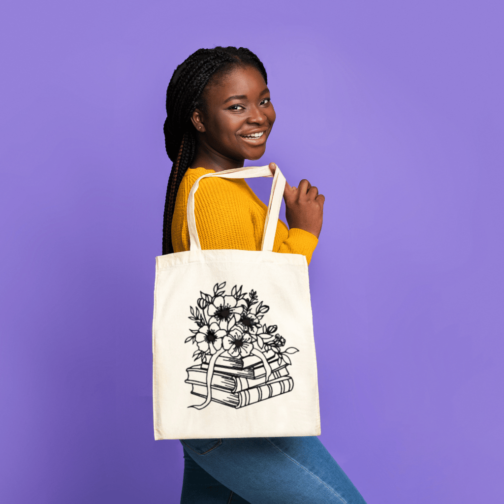 Woman holding a tote bag with a floral and book design against a purple background