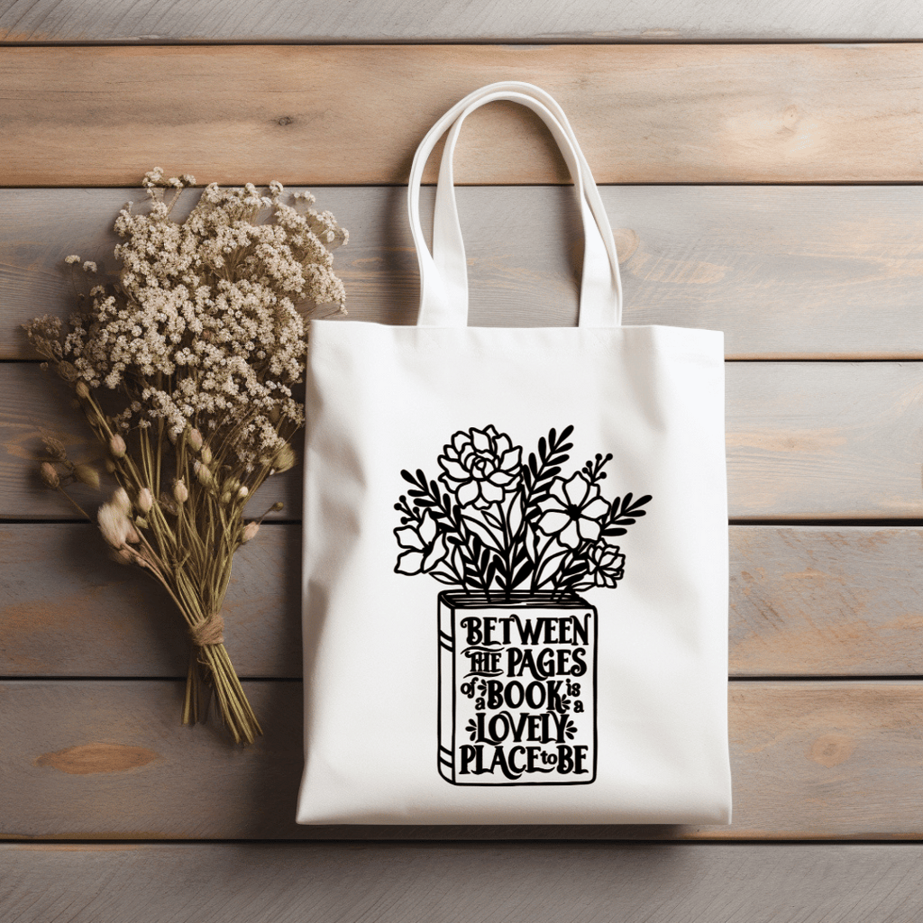 Natural colored canvas tote bag with floral design and text on a wooden surface with dried flowers.