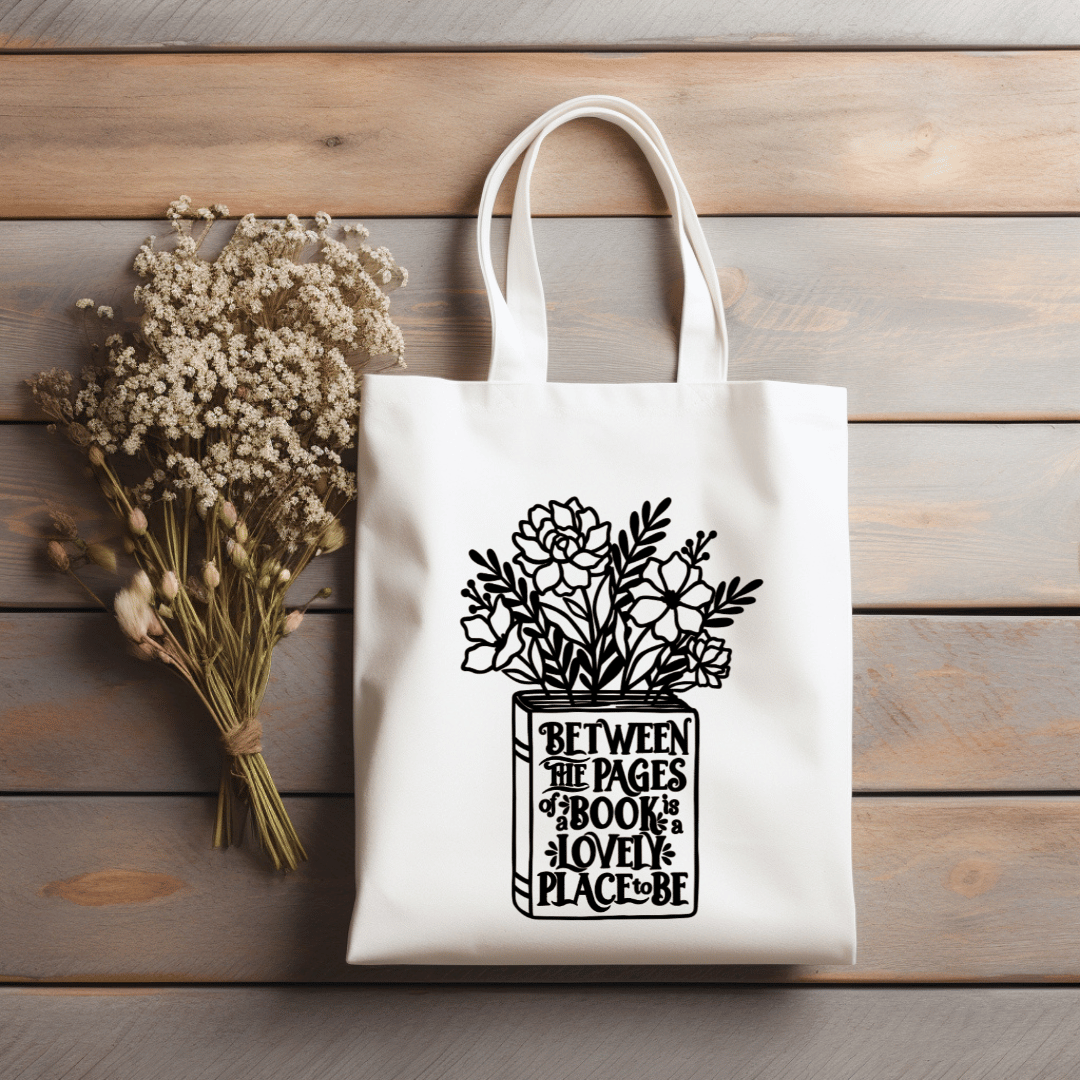 Natural colored canvas tote bag with floral design and text on a wooden surface with dried flowers.