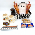 Halloween-themed gift set with mugs, hot cocoa, and snacks on a white background