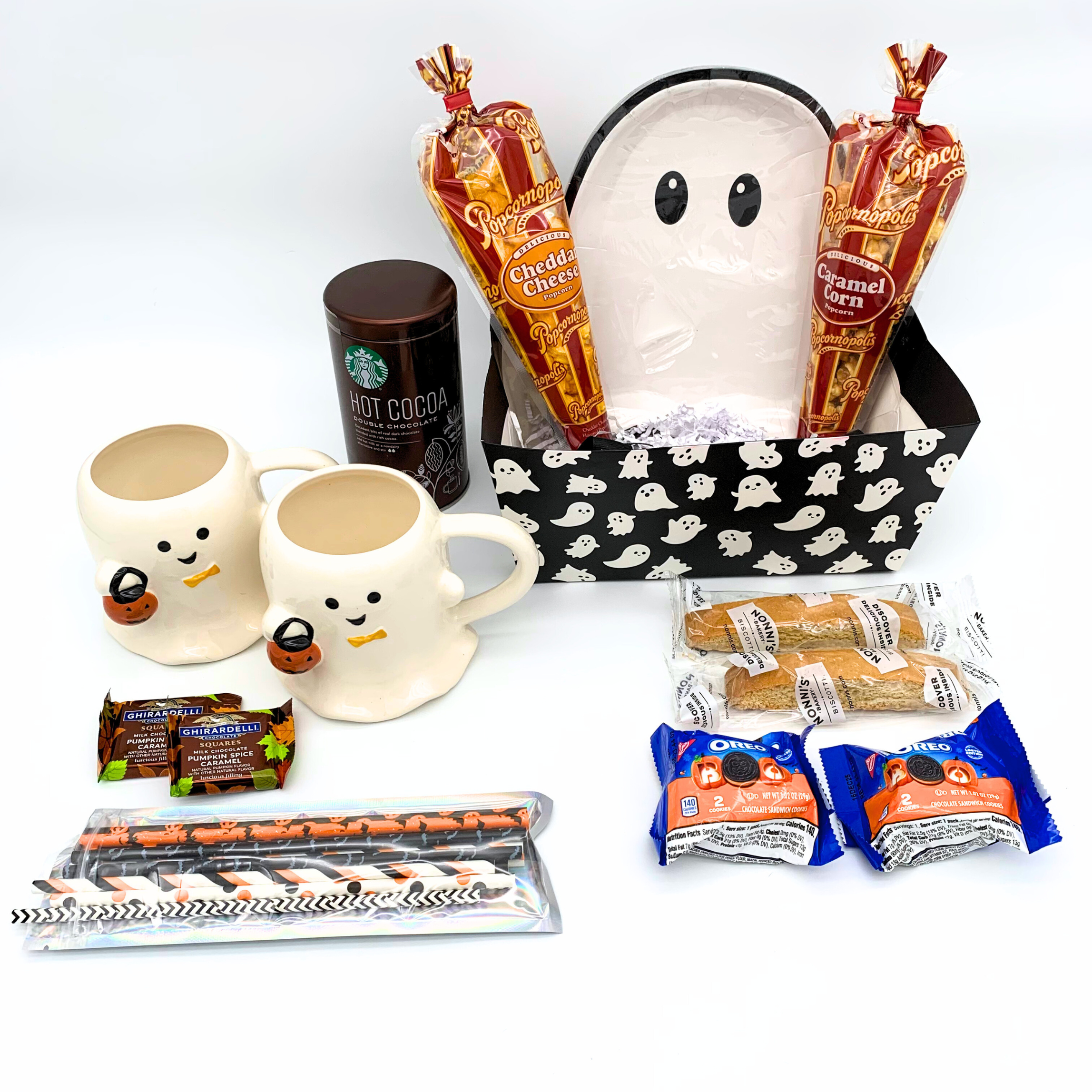 Halloween-themed gift set with mugs, hot cocoa, and snacks on a white background