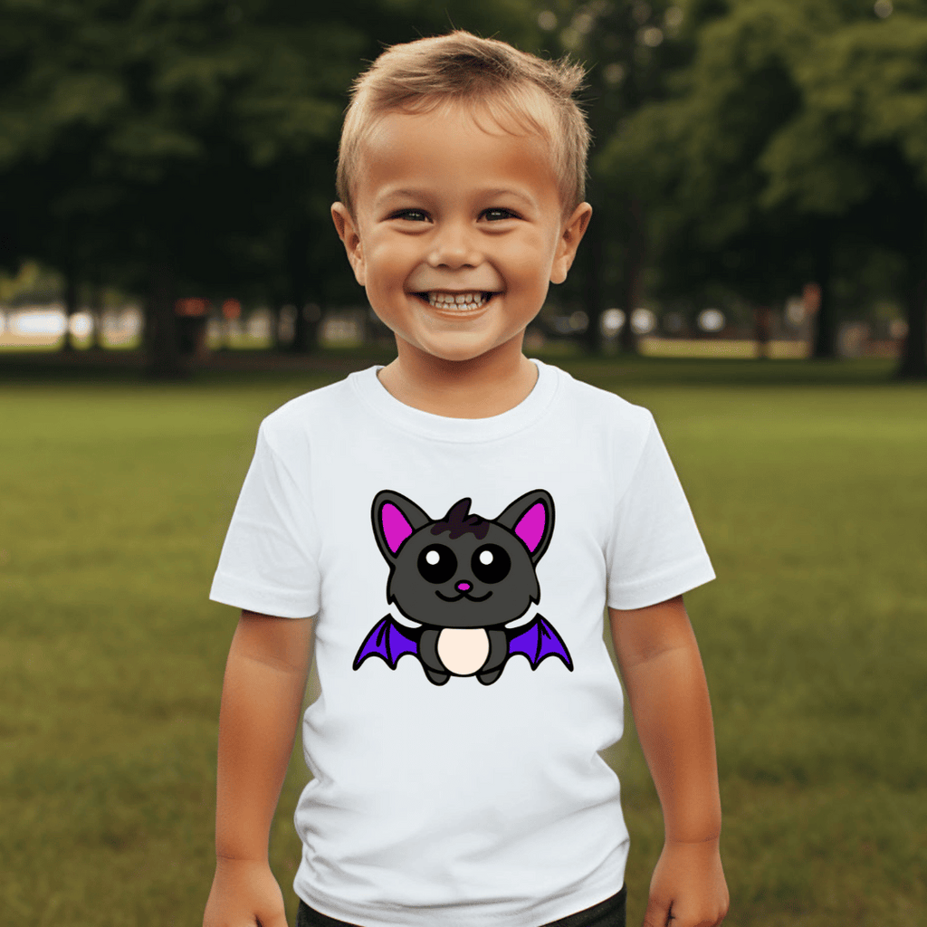 Child wearing a white t-shirt with a cartoon bat design outdoors.