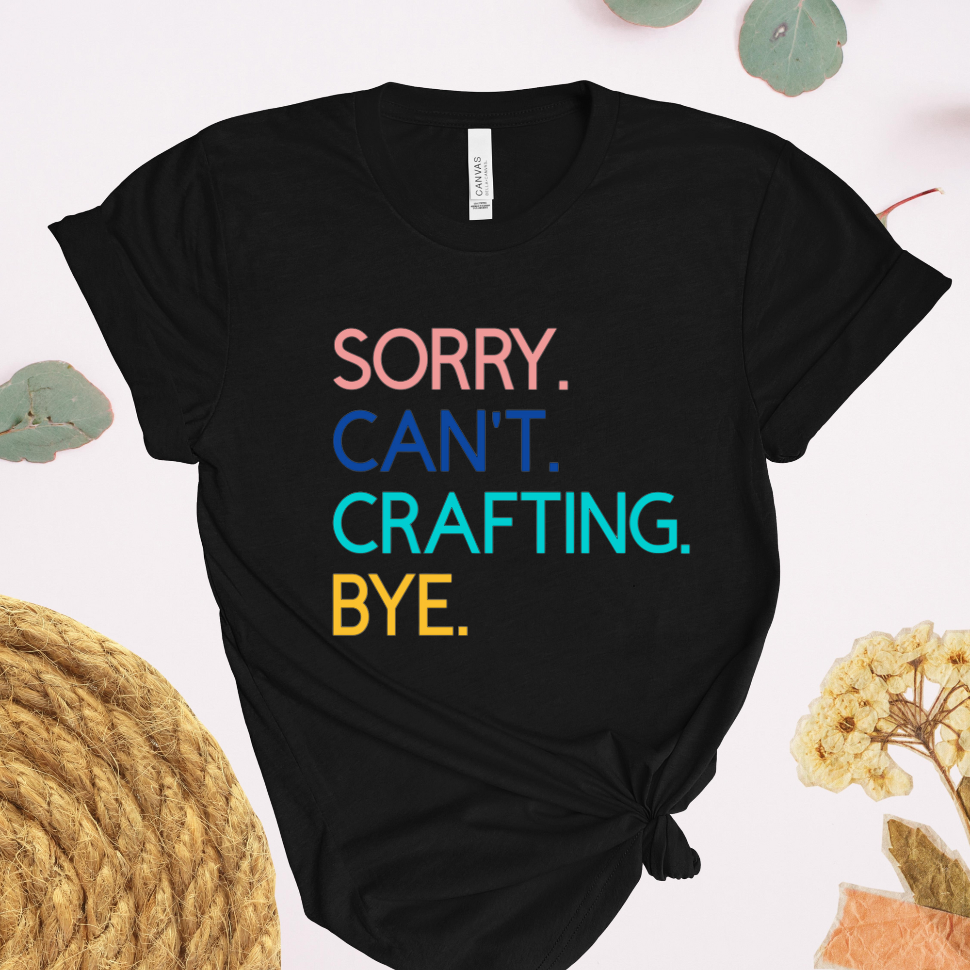 A black t-shirt with the text 'Sorry. Can't. Crafting. Bye.', each line with a different color text.