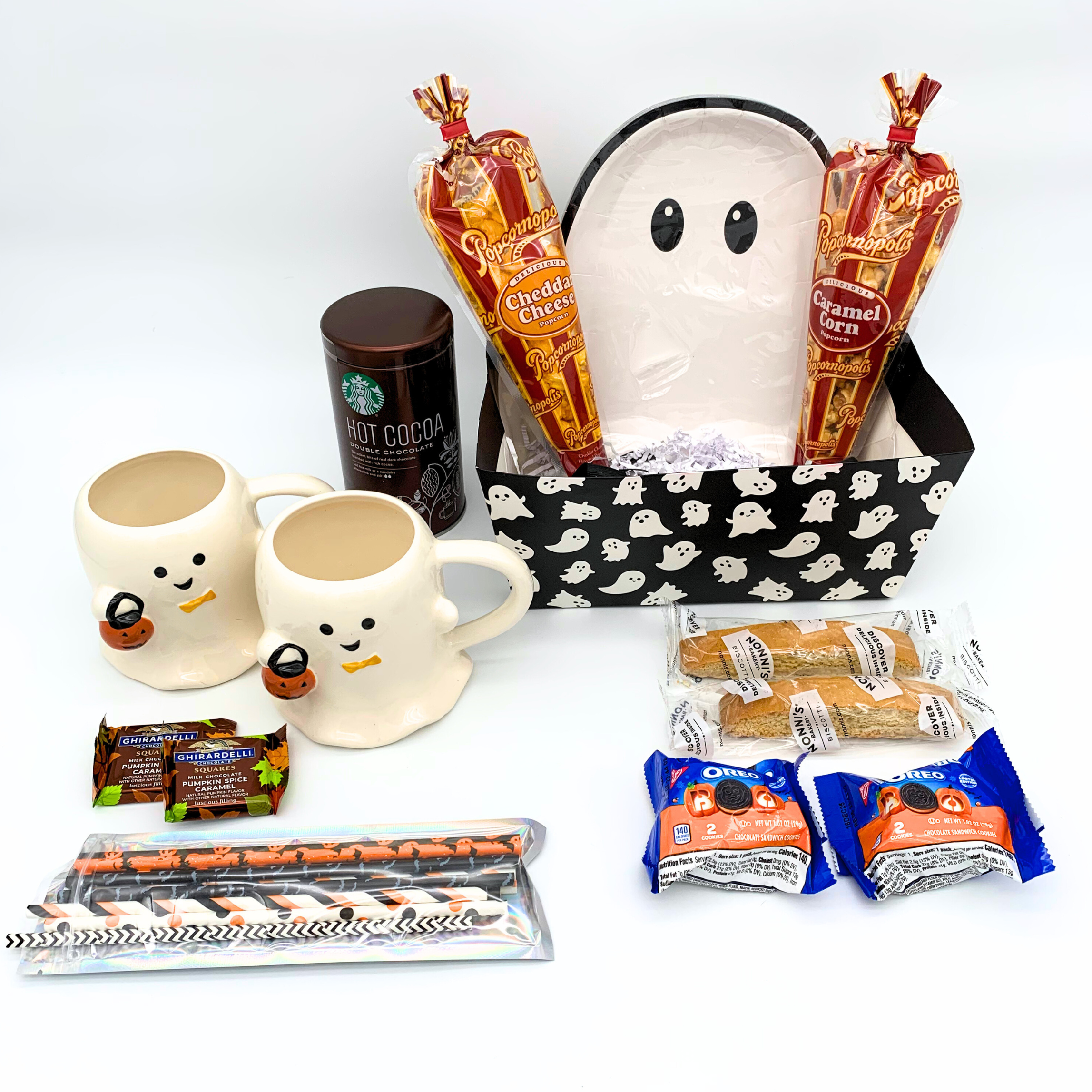 Halloween-themed gift set with ghost-shaped basket, mugs, and snacks on a white background