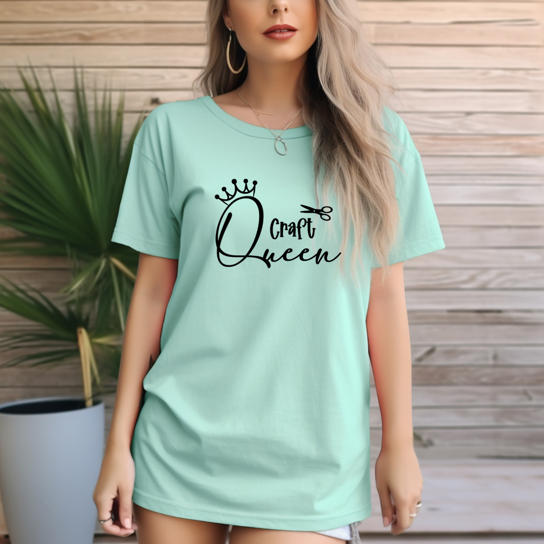 Woman wearing a light green t-shirt with 'Craft Queen' text, standing against a wooden wall.