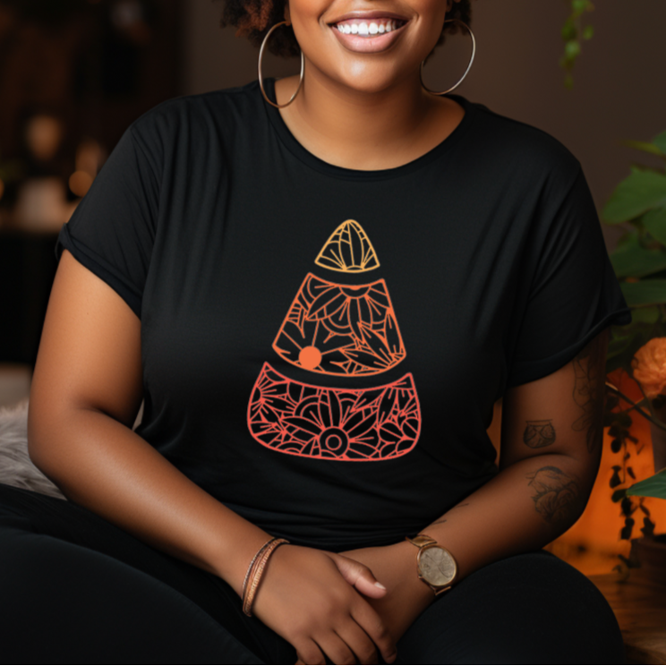 Woman wearing a black t-shirt with a geometric design, sitting in a room with plants.