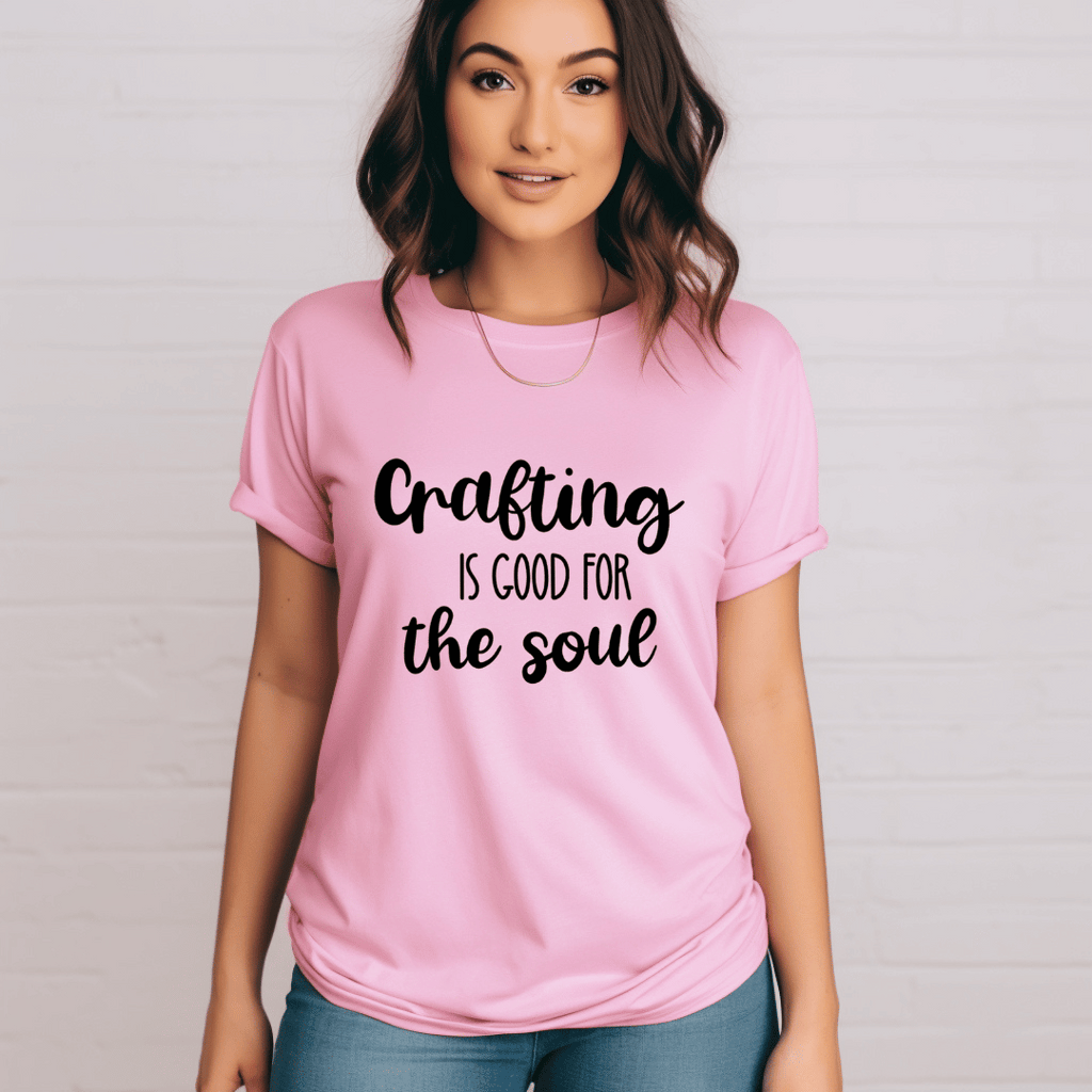 Person wearing a pink t-shirt with 'Crafting is good for the soul' text on a plain background