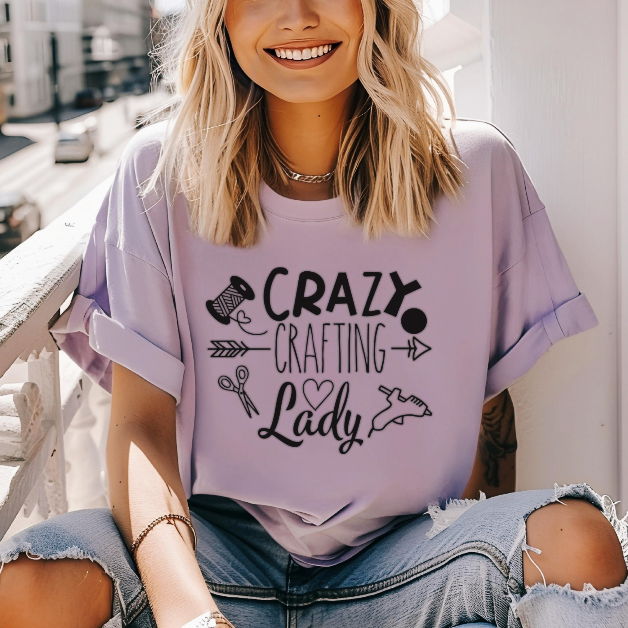 Person wearing a purple t-shirt with 'Crazy Crafting Lady' text, sitting outdoors.