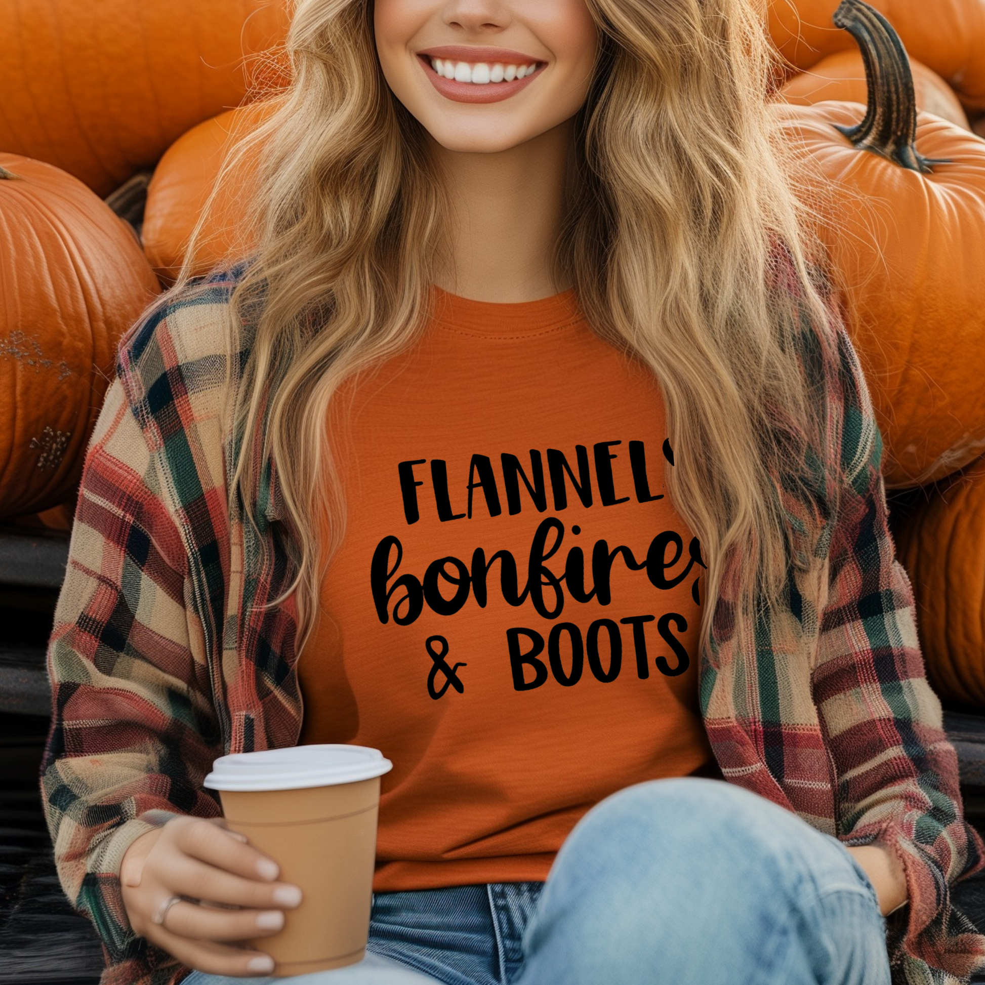 A woman smiling and sitting in a truck, wearing a green t-shirt with the text 'FLANNELS BONFIRES & BOOTS' printed on it, surrounded by pumpkins.