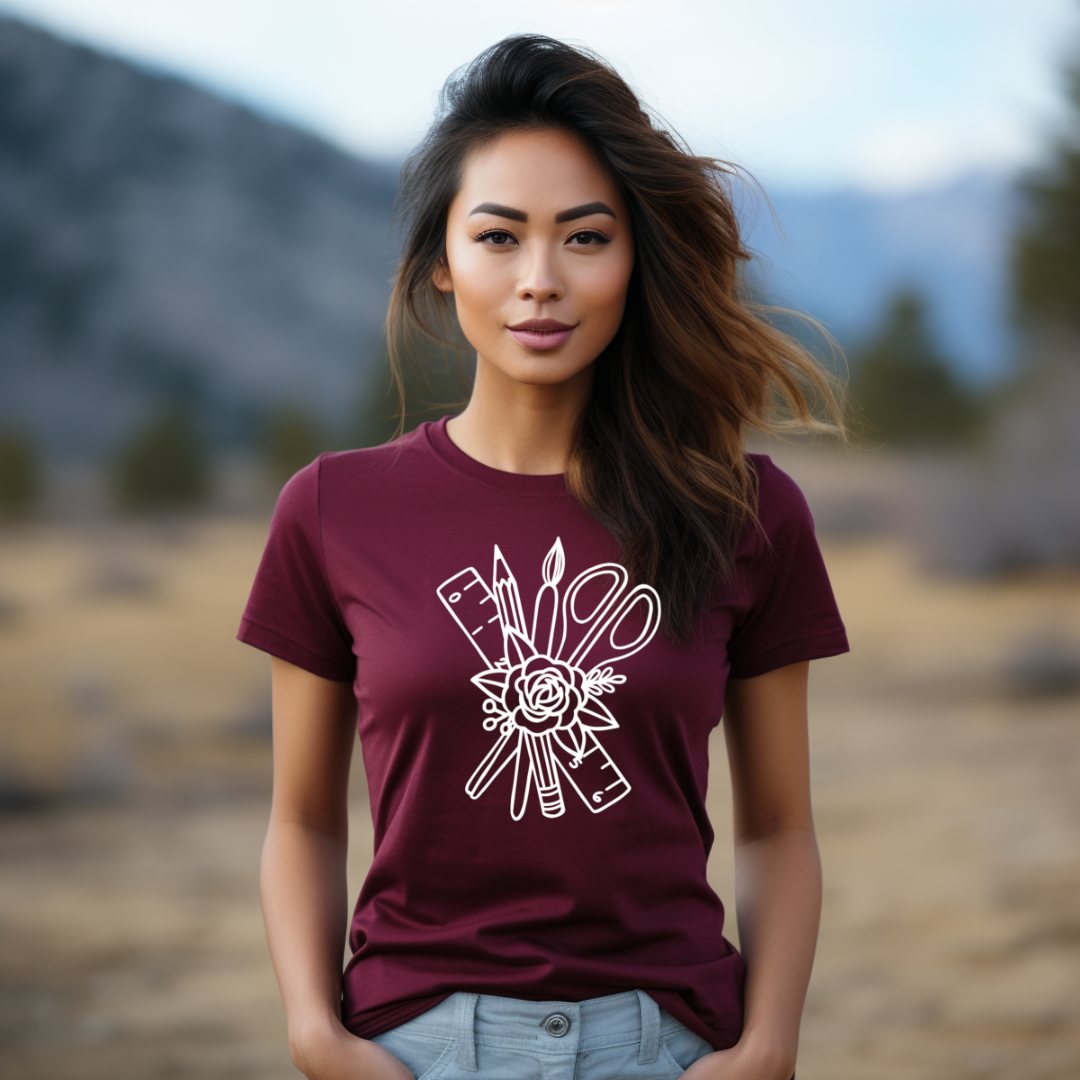 Woman wearing a maroon t-shirt with a white graphic design in a natural setting