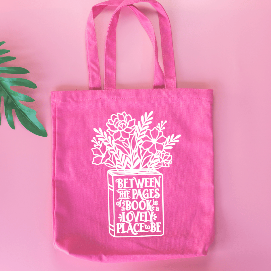 Pink tote bag with floral design and text on a pink background