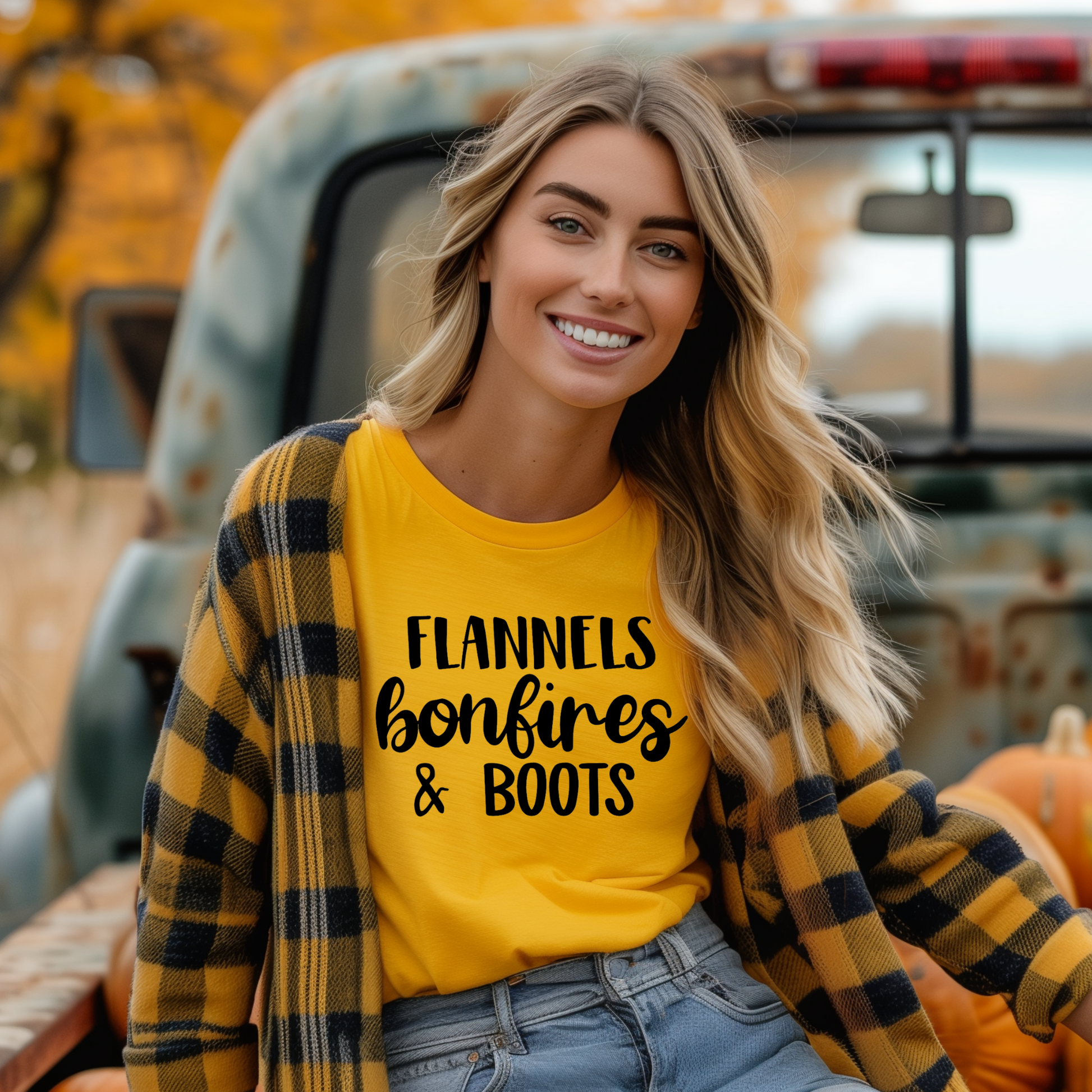 A woman smiling and sitting in a truck, wearing a green t-shirt with the text 'FLANNELS BONFIRES & BOOTS' printed on it, surrounded by pumpkins.