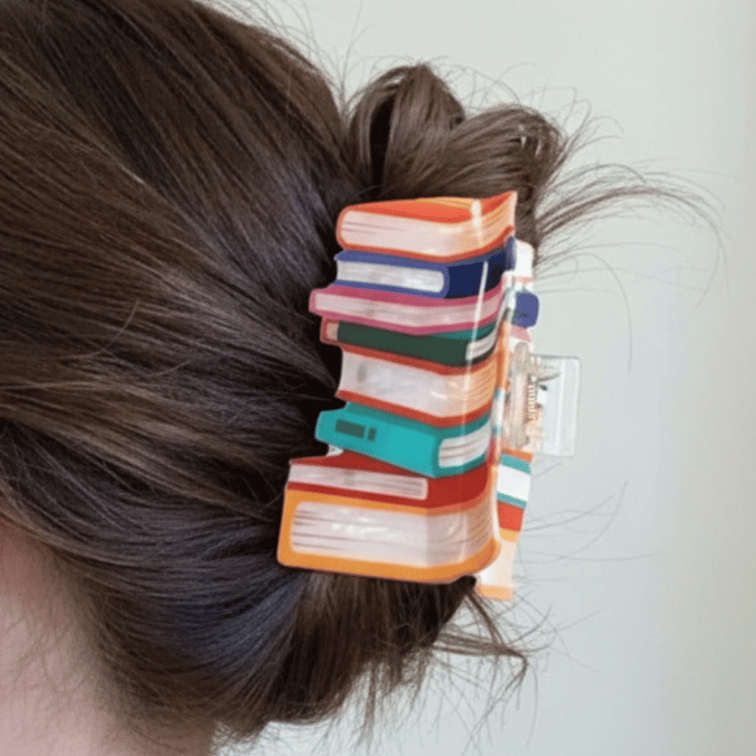 Colorful hair clip with book design in a person's hair against a light background