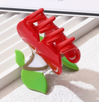 Red and green hair clip on a textured surface with a window in the background