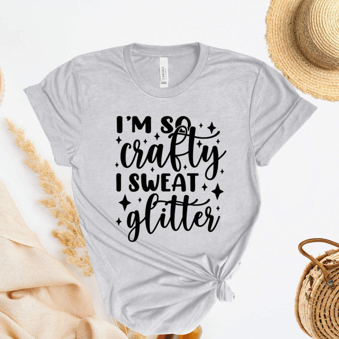 Gray t-shirt with 'I'm so crafty I sweat glitter' text on a white background