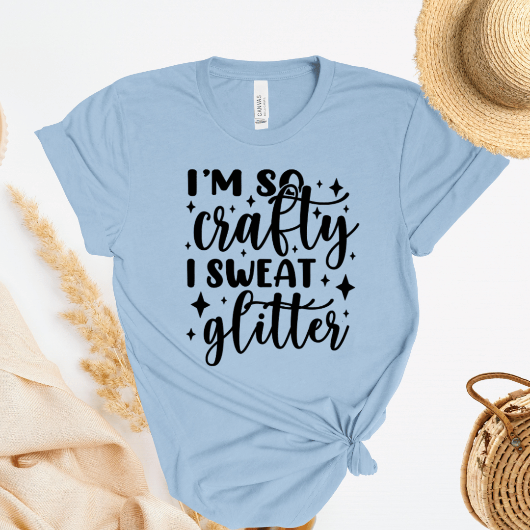 Light blue t-shirt with 'I'm so crafty I sweat glitter' text on a white background