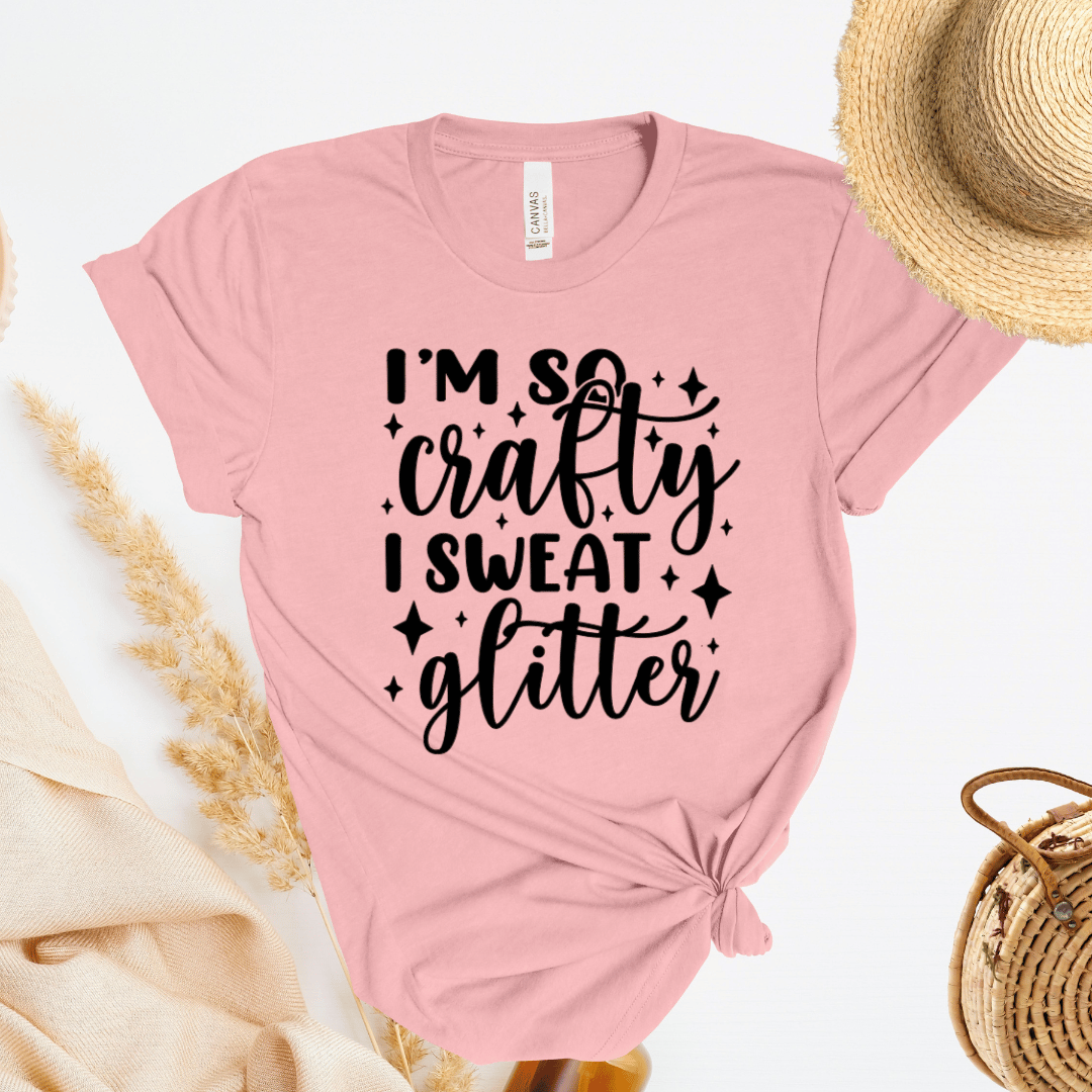 Light pink t-shirt with 'I'm so crafty I sweat glitter' text on a light background