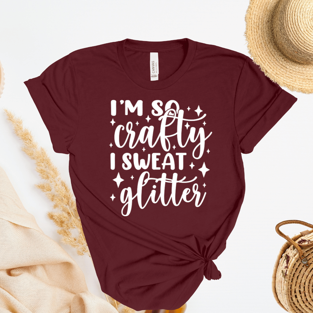 Maroon t-shirt with 'I'm so crafty I sweat glitter' text on a light background