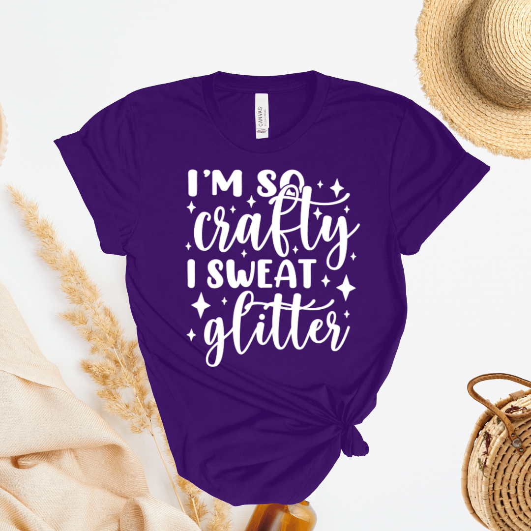 Purple t-shirt with 'I'm so crafty I sweat glitter' text on a light background