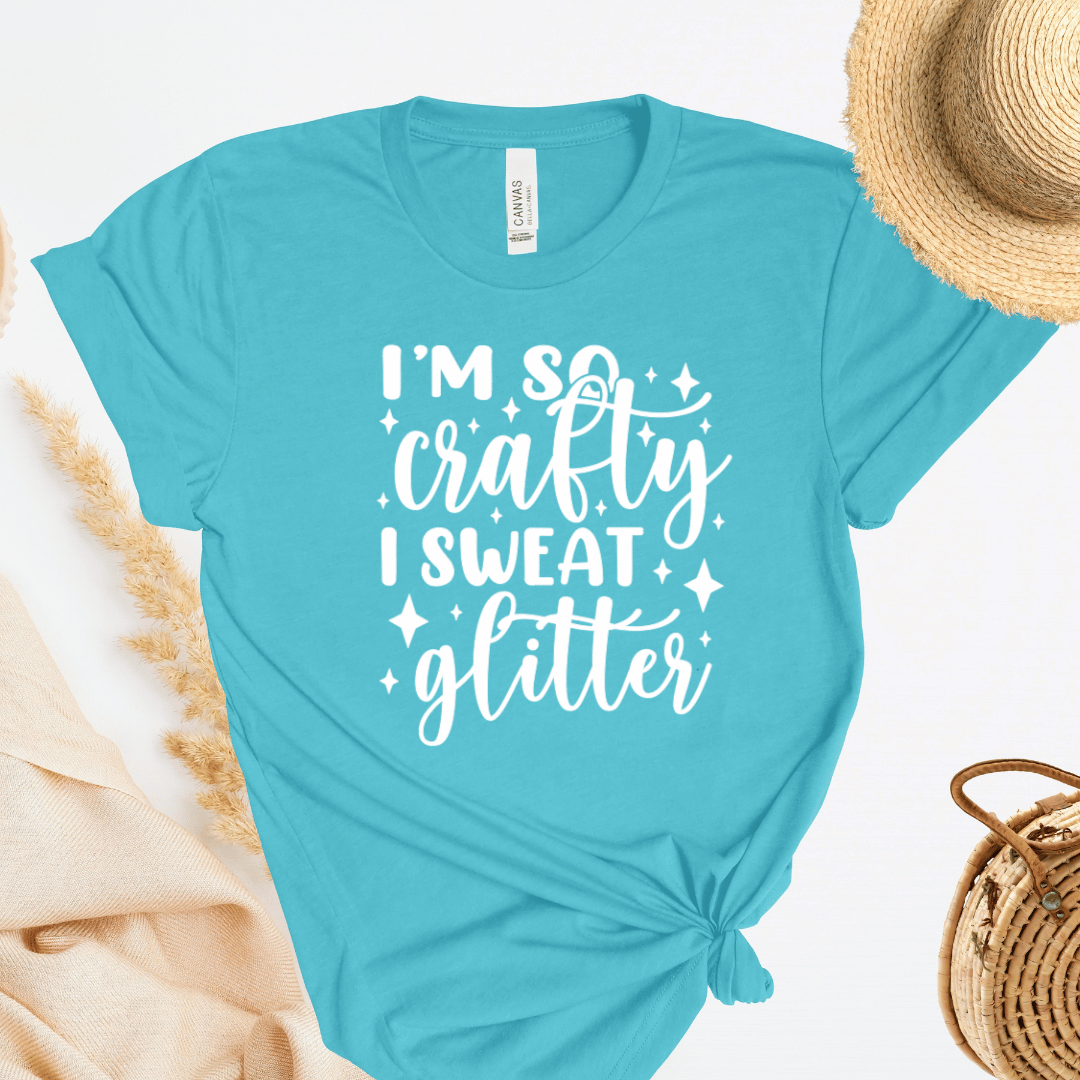 Turquoise t-shirt with 'I'm so crafty I sweat glitter' text on a white background