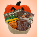 Jack-o'-lantern coloring book gift set in a tan rope basket with an orange pumpkin pillow, two coloring books, brown mug, and markers