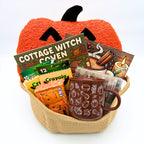 Halloween pumpkin coloring gift basket with a jack-o'-lantern pillow, two coloring books, brown fall mug, and marshmallow pumpkins