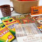 Neutral gel pen set, fine line markers, and colored pencils in front of the coloring books, with the mug and pumpkin pillow behind
