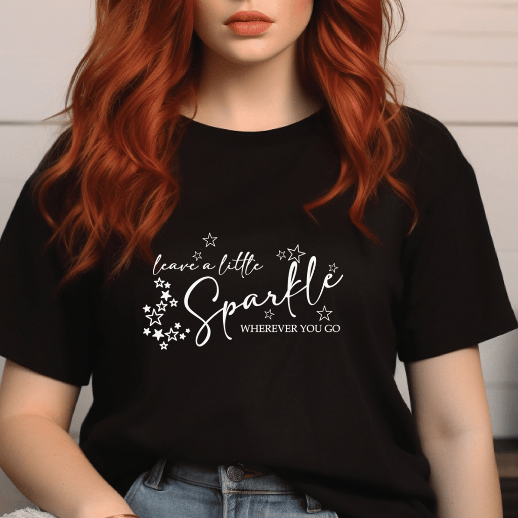 Person wearing a black t-shirt with 'leave a little sparkle wherever you go' text