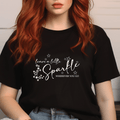 Person wearing a black t-shirt with 'leave a little sparkle wherever you go' text