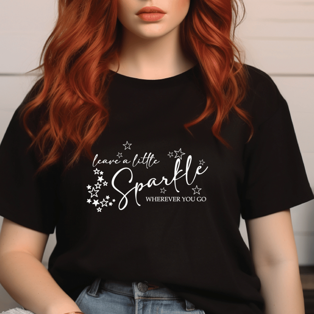 Person wearing a black t-shirt with 'leave a little sparkle wherever you go' text