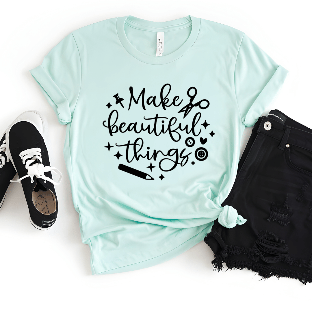 Mint green crafting t-shirt with 'Make beautiful things' text, paired with black shorts and sneakers on a white background