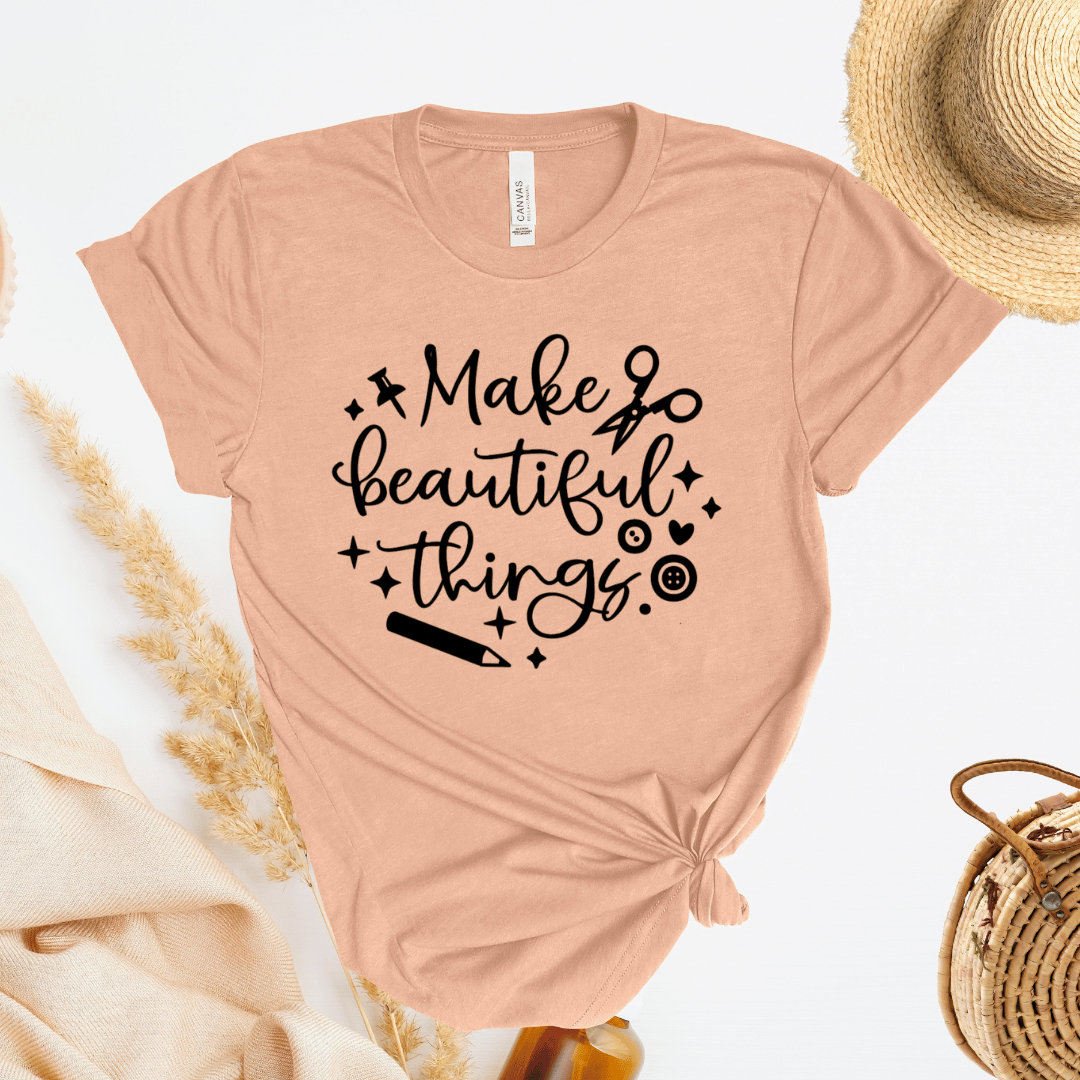 Peach colored t-shirt with 'Make beautiful things' text on a light background