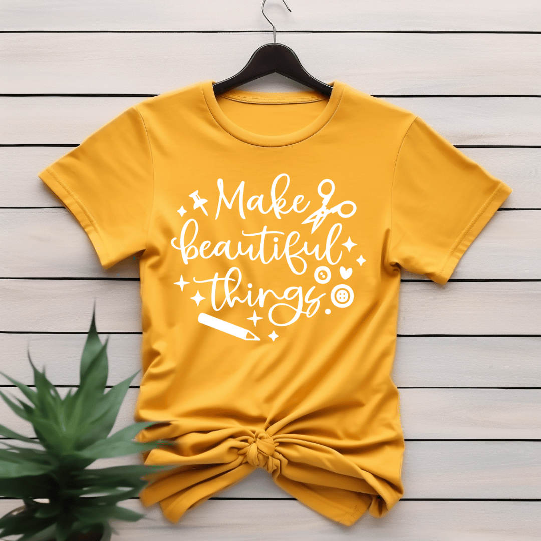Yellow crafting themed t-shirt with 'Make beautiful things' text on a wooden surface with a plant.