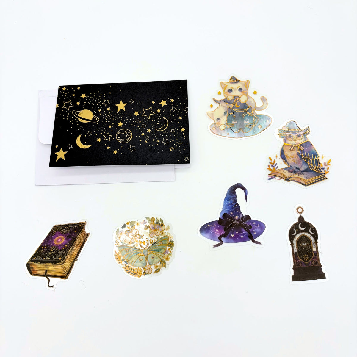 Gold and black celestial greeting card with envelope and six witchy stickers including cats, an owl, a spell book and a witch hat