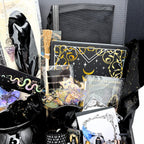 Mystical witchy gift box packed in celestial tissue with the journal, pendulum, broom, cauldron mug and sticker packs visible